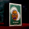 A boxed matchbox product standing upright on a red surface against a dark smoky background. The front cover is green and white with a stylized illustrated face and the text 'THE SURVIVOR' and 'MATCHBOX'.
