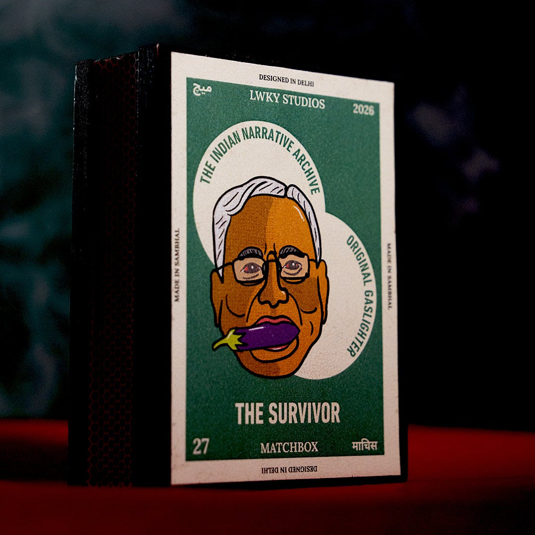 A boxed matchbox product standing upright on a red surface against a dark smoky background. The front cover is green and white with a stylized illustrated face and the text 'THE SURVIVOR' and 'MATCHBOX'.